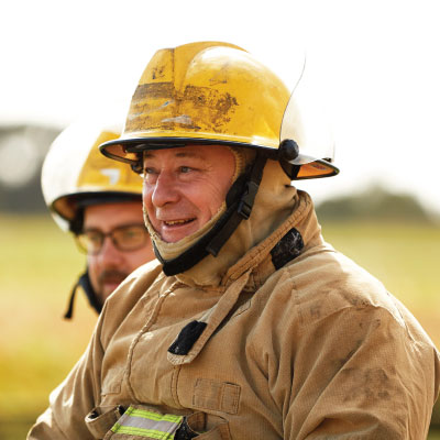 Firefighter in full gear smiling at something off camera